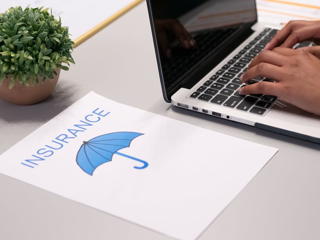 Image showing insurance contract next to a person typing on laptop